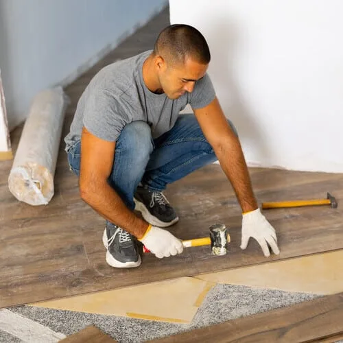 Contractor installing hardwood flooring during home remodeling project