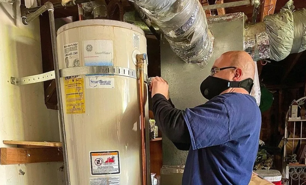 Plumber servicing a tank water heater with a wrench in San Francisco