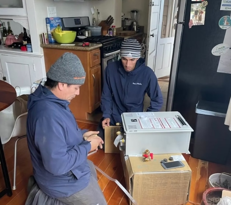 Heise's Plumbing technicians installing a tankless water heater in a San Francisco kitchen
