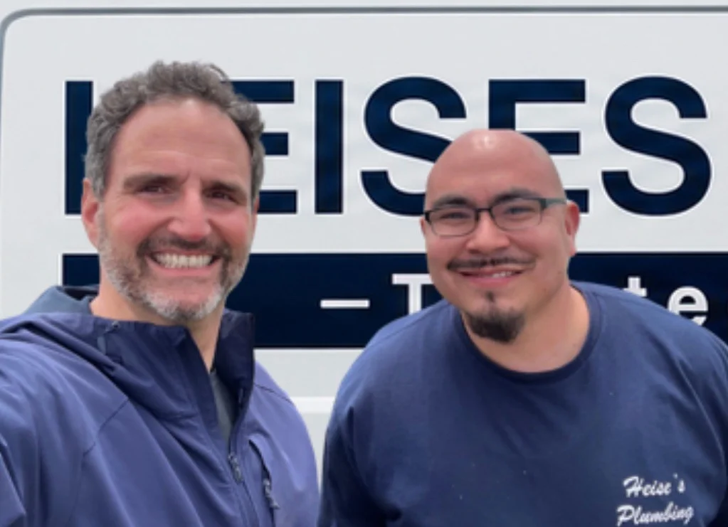 Co-owners Michael Giometti and Sergio Cabrales standing in front of a Heise's Plumbing service van