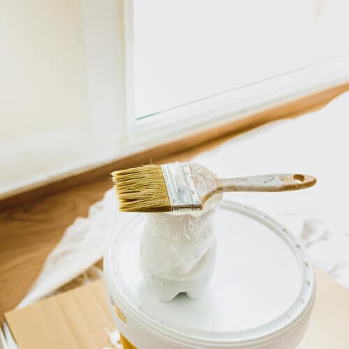 Paintbrush rests on can of paint.